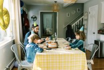 Une petite famille manger un gâteau d'anniversaire à la table et célébrer — Photo de stock