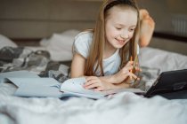 Mädchen liegt auf dem Bett umgeben von Notizbüchern — Stockfoto