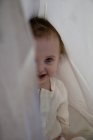 Baby girl hiding behind sheet — Stock Photo