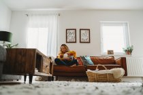 Blick ins Wohnzimmer: Weiße Mutter stillt Neugeborenes auf der Couch — Stockfoto