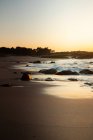 Sunset on beach, rocky coast of sea. — Stock Photo