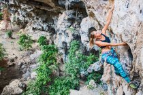 Mujer escalando escarpado acantilado de piedra caliza en Laos - foto de stock