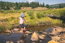 Junges Mädchen überquert einen Fluss in der Wildnis von Colorado — Stockfoto