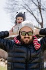 Bebê feliz nos ombros do pai no quintal na tarde fria — Fotografia de Stock