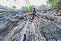 Woman climbing steep limestone cliff in Laos — Stock Photo