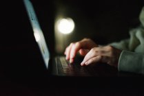 Mulher anônima trabalhando no laptop à noite — Fotografia de Stock
