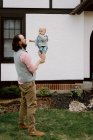 Fun dad playing with confused baby son in front yard in spring — Stock Photo