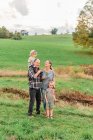 Dos niños pequeños y sus abuelos en un paseo por un prado florido - foto de stock