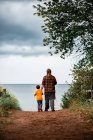Un padre e un figlio che camminano insieme lungo un sentiero verso la spiaggia — Foto stock