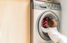 Petite fille regardant la machine à laver — Photo de stock