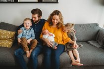 Glückliche weiße Familie mit kleinen Kindern und Baby im Wohnzimmer — Stockfoto