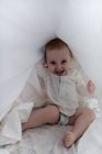 Bebê menina escondido sob o lençol — Fotografia de Stock