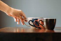 Main tenant une tasse de cappuccino sur une table en bois dans un café ou un café — Photo de stock