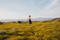 Молода жінка в полі з квітами позує — стокове фото