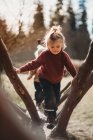 Criança subindo no tronco na floresta em um dia ensolarado de inverno — Fotografia de Stock