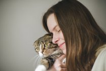 Mujer joven sosteniendo hermoso gato en blanco fondo - foto de stock