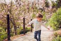 Niño pequeño en un floreciente parque de flores de cerezo - foto de stock