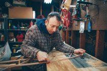 Белый мужчина средних лет работает на маленьком кусочке деревянного самолета в своем гараже. — стоковое фото