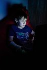 Boy sittingand usando um laptop, olhando para a tela do computador — Fotografia de Stock