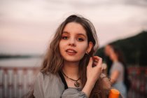 Портрет дівчини-підлітка, що стоїть на мосту на заході сонця влітку — стокове фото