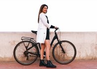 Приваблива молода жінка з велосипедом ходить по гавані — стокове фото