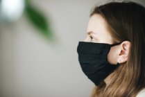 Giovane donna sullo sfondo bianco con indosso una maschera — Foto stock