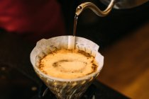 Um tiro de perto da mão de um barista segurando uma xícara de café vazia na mesa — Fotografia de Stock