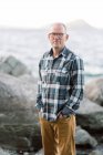 Homem de meia idade em pé perto de uma praia rochosa na Nova Inglaterra sorrindo — Fotografia de Stock
