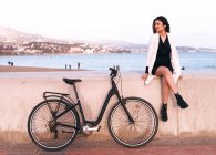 Приваблива молода жінка з велосипедом ходить по гавані — стокове фото