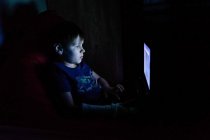 Junge sitzt am Laptop und schaut auf den Computerbildschirm — Stockfoto