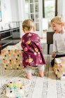 Niños desenvolviendo regalos de cumpleaños en la sala de estar y siendo alegres - foto de stock