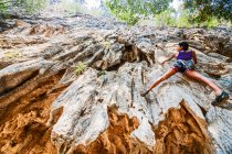 Женщина карабкается на крутую известняковую скалу в Лаосе — стоковое фото