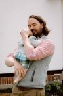 Милый отец обнимает маленького сына в пастельных тонах на улице весной. — стоковое фото
