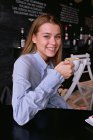 Sorrindo linda menina tomando uma xícara de café em um café — Fotografia de Stock