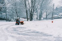 Человек на тракторе пашет снег на подъездной дорожке во время северо-восточного шторма — стоковое фото