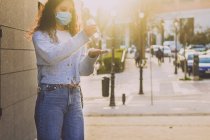 Молодая женщина нанесла гель для дезинфекции на руки на улице — стоковое фото