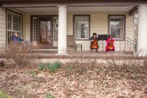 Vista à distância de duas crianças dando concerto de violoncelo para mulher idosa — Fotografia de Stock