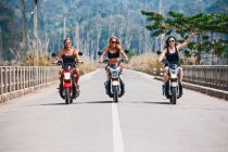 Три подруги едут на скутерах по шоссе в Лаосе — стоковое фото