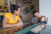Zwei Frauen und ein Baby im Café reden und lachen — Stockfoto