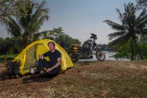Junger Mann im Zelt neben Motorrad — Stockfoto