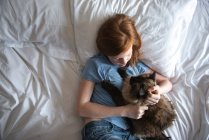 Jovem com gatinho bonito deitado na cama e abraçando. família feliz com gato no quarto. — Fotografia de Stock