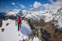 Чоловік піднімається на сніжну гору в сонячний день у Деверо (Італія).. — стокове фото