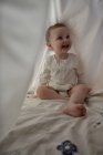Bébé fille se cachant sous la feuille blanche — Photo de stock