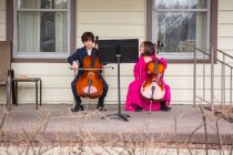 Двое детей дают концерт на виолончели — стоковое фото