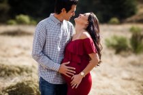 Marido y esposa embarazada posando en el campo en San Diego - foto de stock