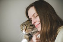 Mujer joven sosteniendo hermoso gato en blanco fondo - foto de stock