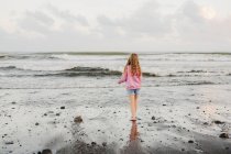 Giovane ragazza in piedi sul bordo delle acque in spiaggia — Foto stock