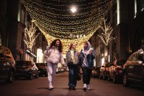 Amigos do sexo feminino falando andando na estrada na cidade durante a noite durante o inverno — Fotografia de Stock