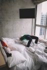 Boy does back bend on bed in modern hotel room — Stock Photo