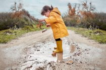 A 2 year old girl playing with a mud puddle — Stock Photo